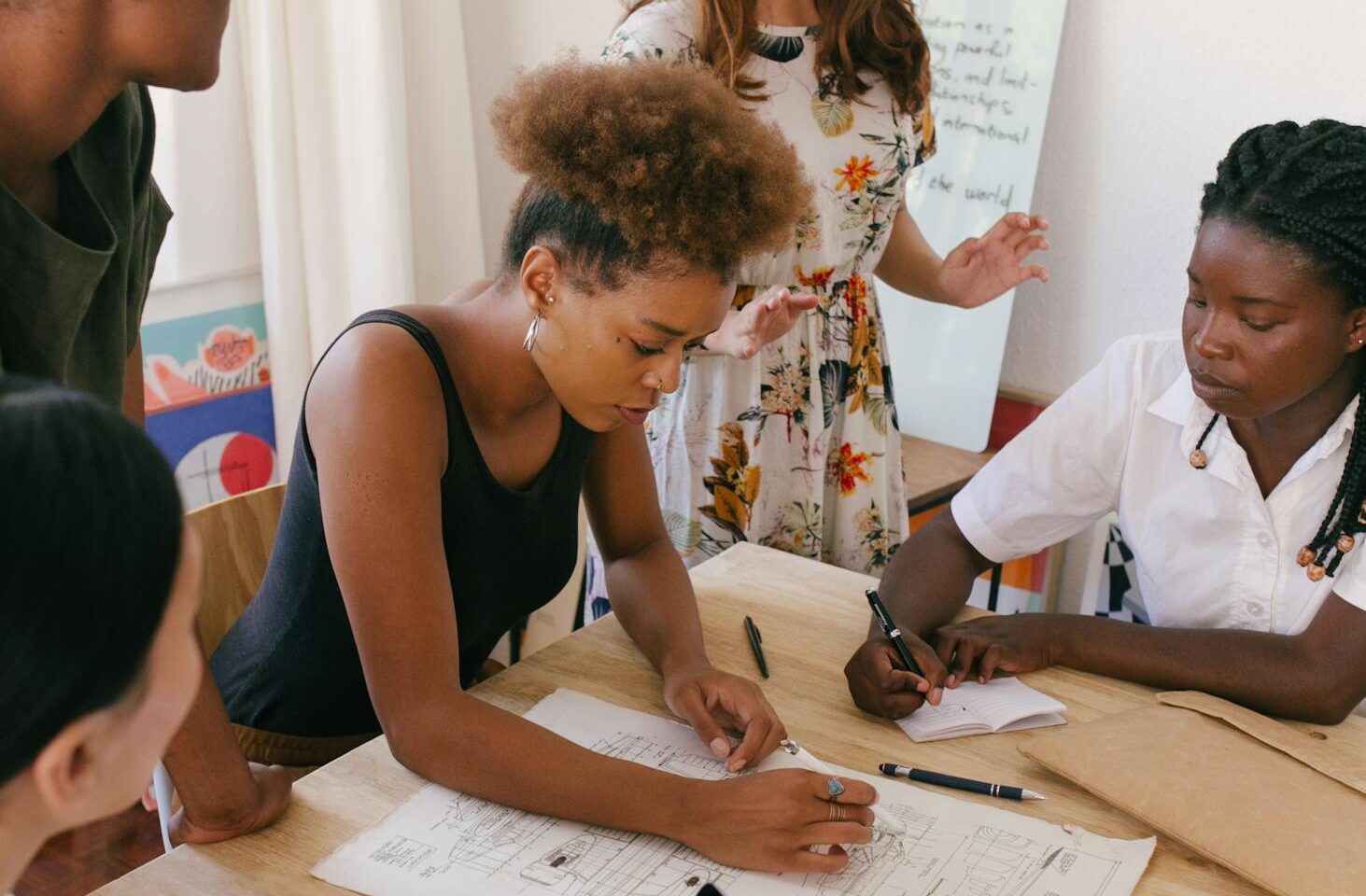 Group of women collaborating on a creative project in a modern office environment.